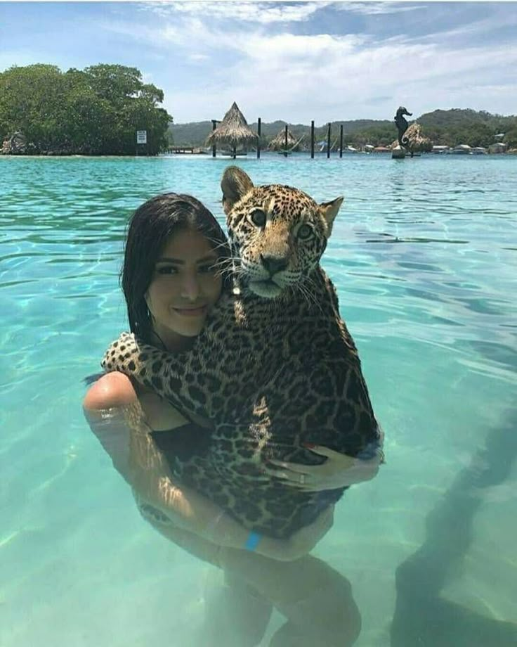 a woman holding a leopard in the water