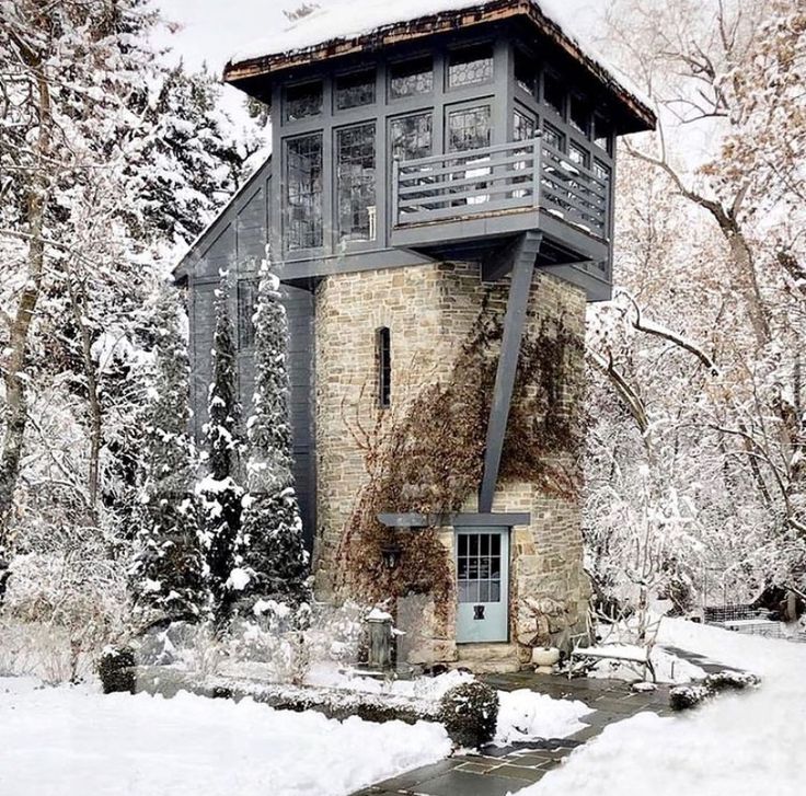 an old stone building with a blue door and window in the middle of snow covered trees