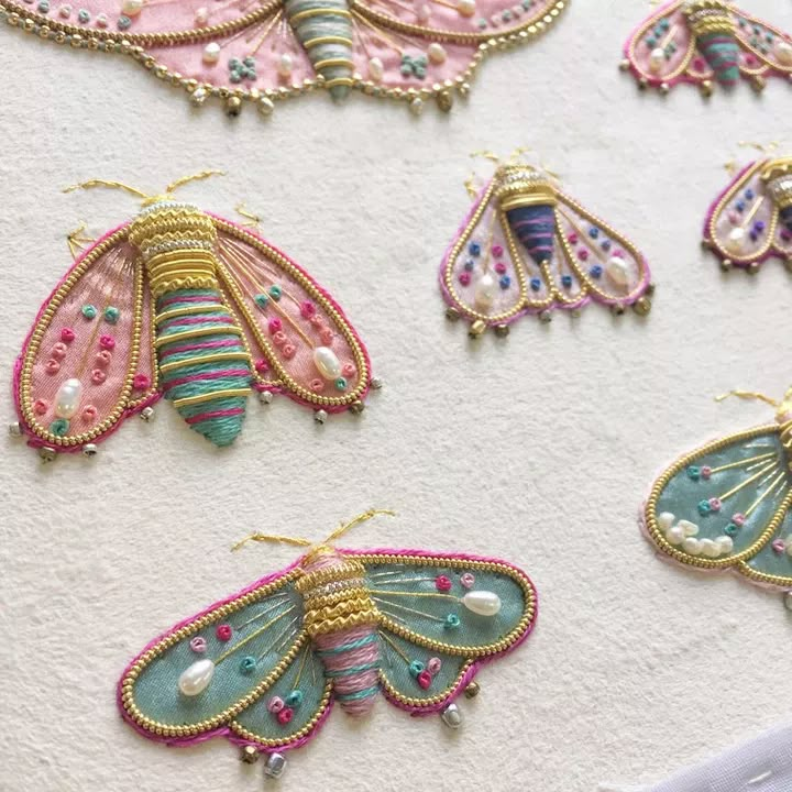 some very pretty colorful butterfly brooches on a white tablecloth with pearls and beads