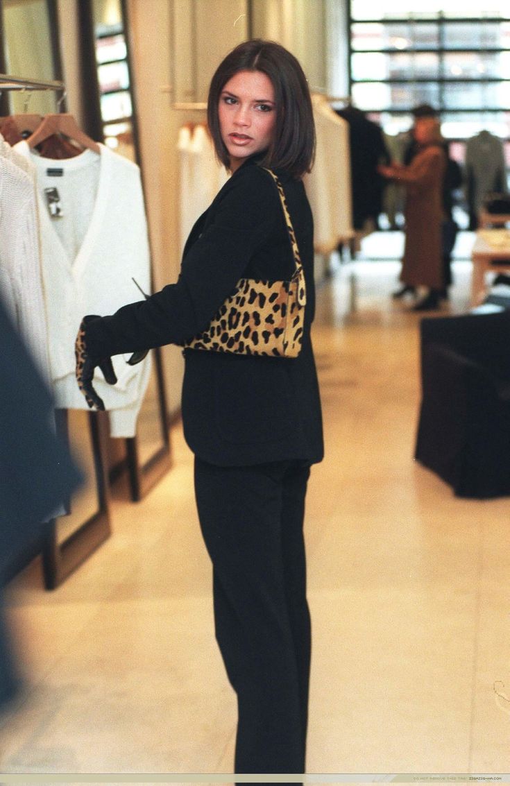 a woman standing in front of a store display with clothes on racks and mannequins behind her