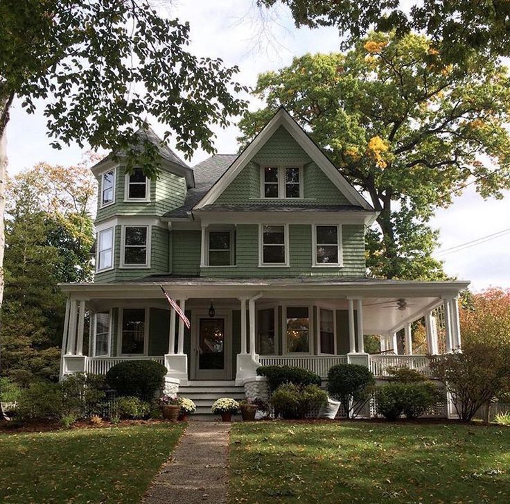 a large green house with white trim and windows