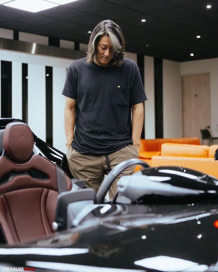 a man standing next to a car in a showroom