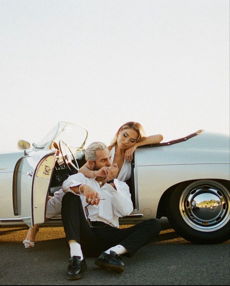 a man and woman sitting in the back of a white car with their arms around each other