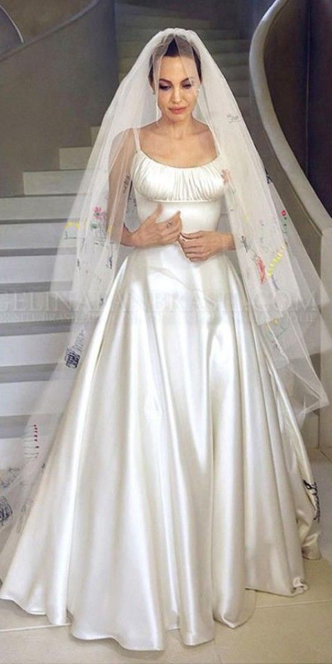 a woman in a white wedding dress standing next to a staircase with her hands on her hips