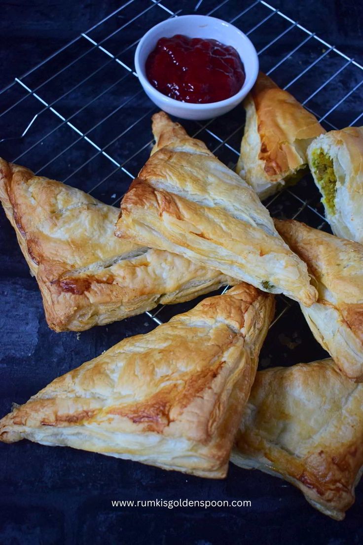 several pastries sitting on a cooling rack next to a bowl of ketchup