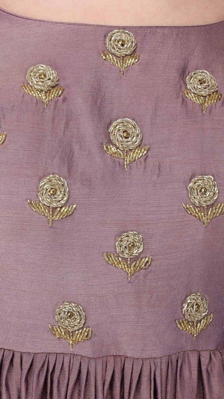 the back of a woman's purple dress with gold embroidered roses and leaves on it