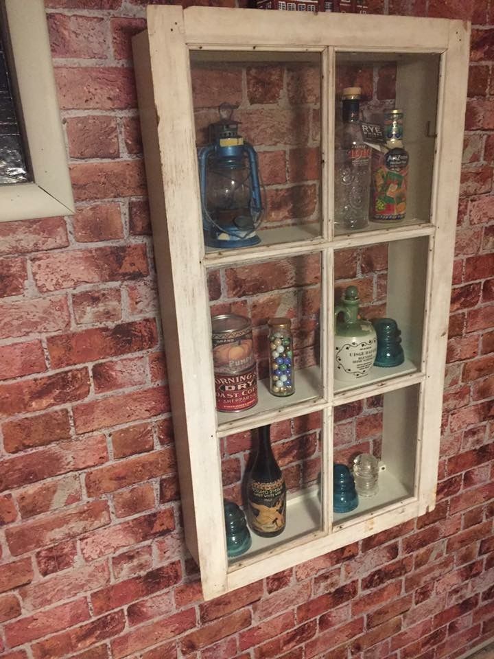 an old window is filled with bottles and jars on the shelf in front of a brick wall