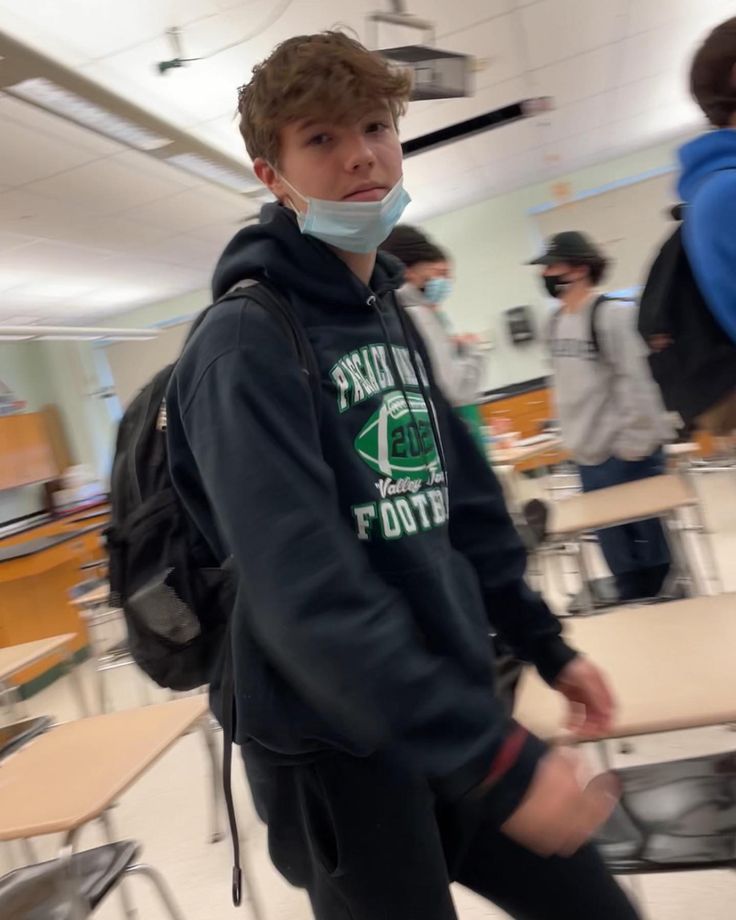 a young man wearing a face mask in a classroom