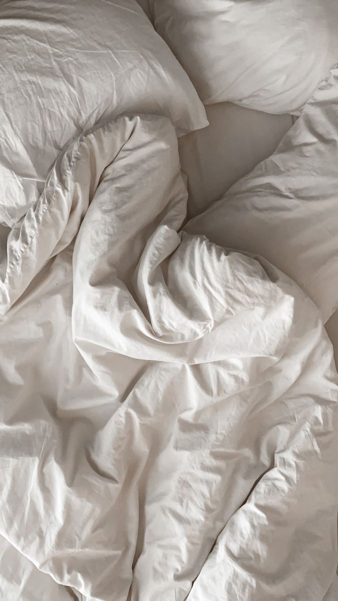 an unmade bed with white sheets and pillows