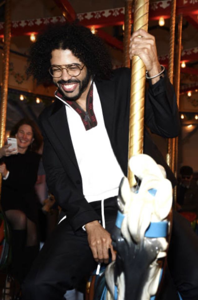 a man on a merry go round at an amusement park with people in the background