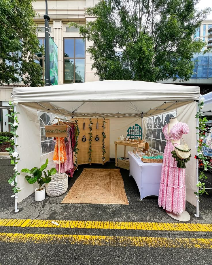 a white tent with clothes hanging from it's sides on the side of a street