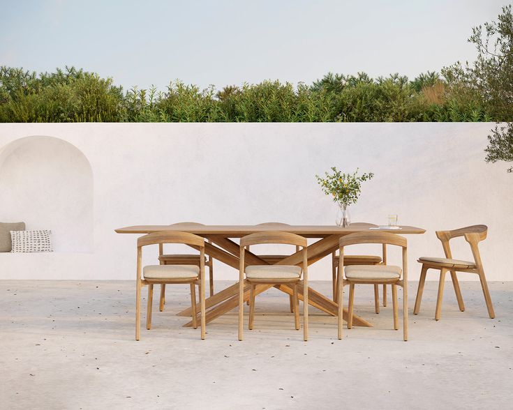 a wooden table and chairs in front of a white wall with an olive tree on it