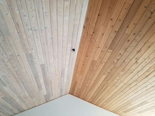 a bed sitting under a wooden ceiling next to a window