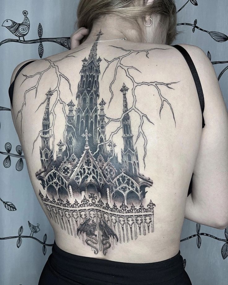 the back of a woman's body with a castle tattoo on it