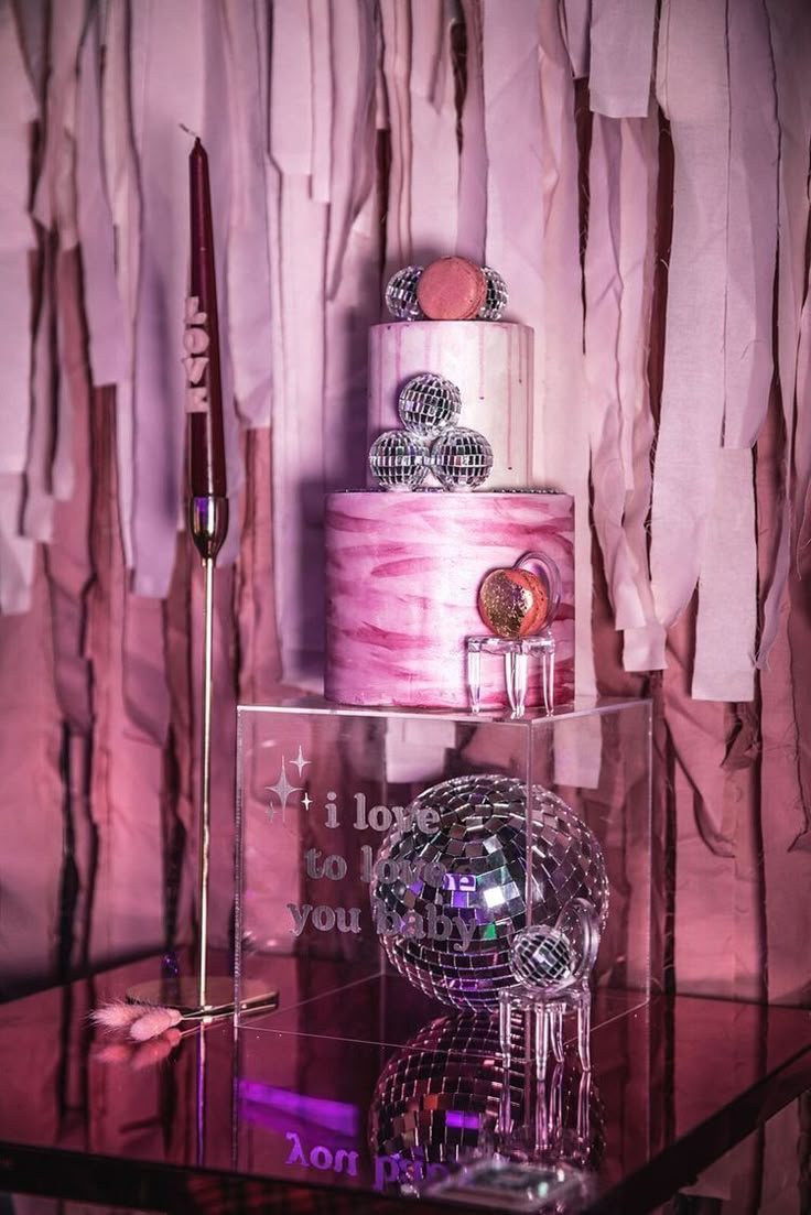 there is a pink cake on top of a glass table with other items around it