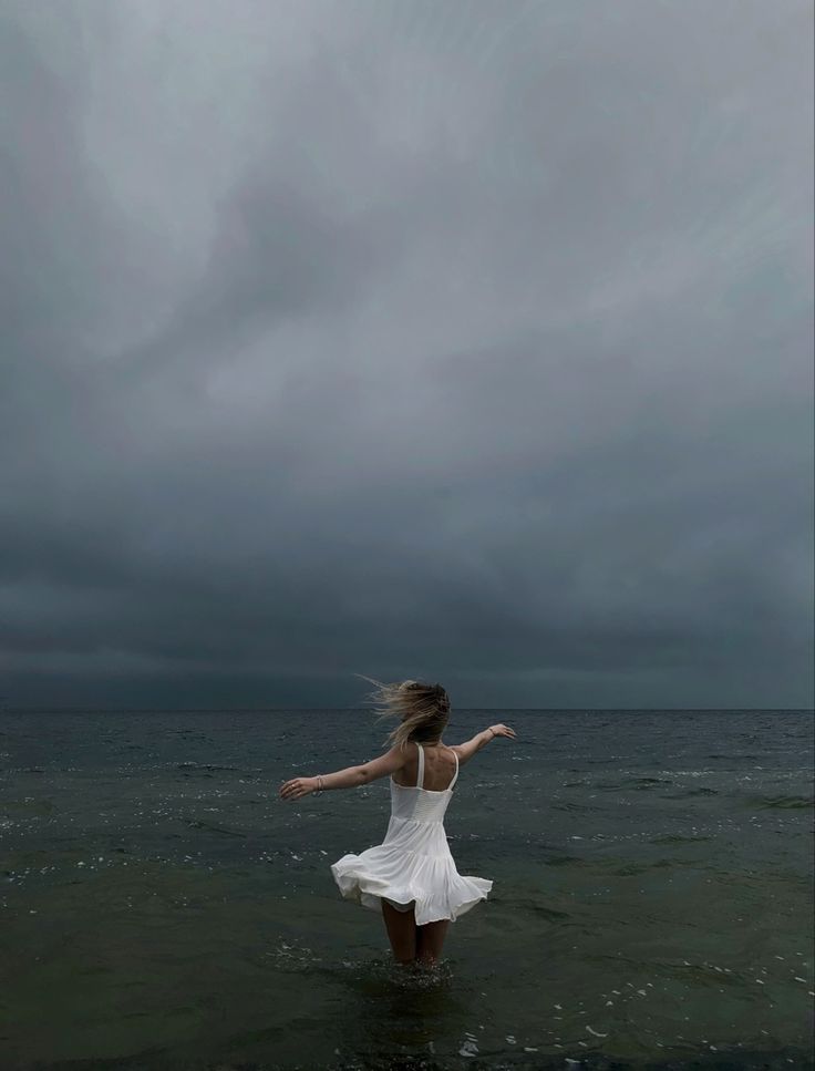 a woman standing in the water with her arms outstretched