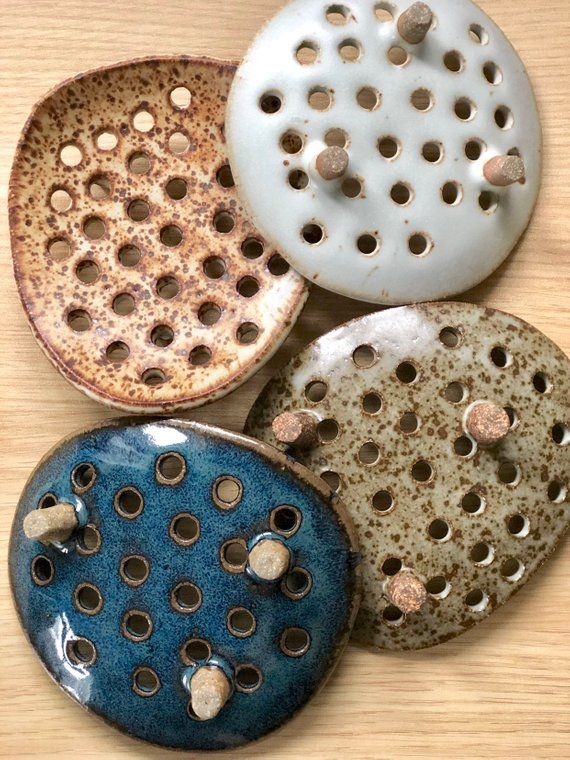 four ceramic plates with holes in them sitting on a wooden table top next to each other