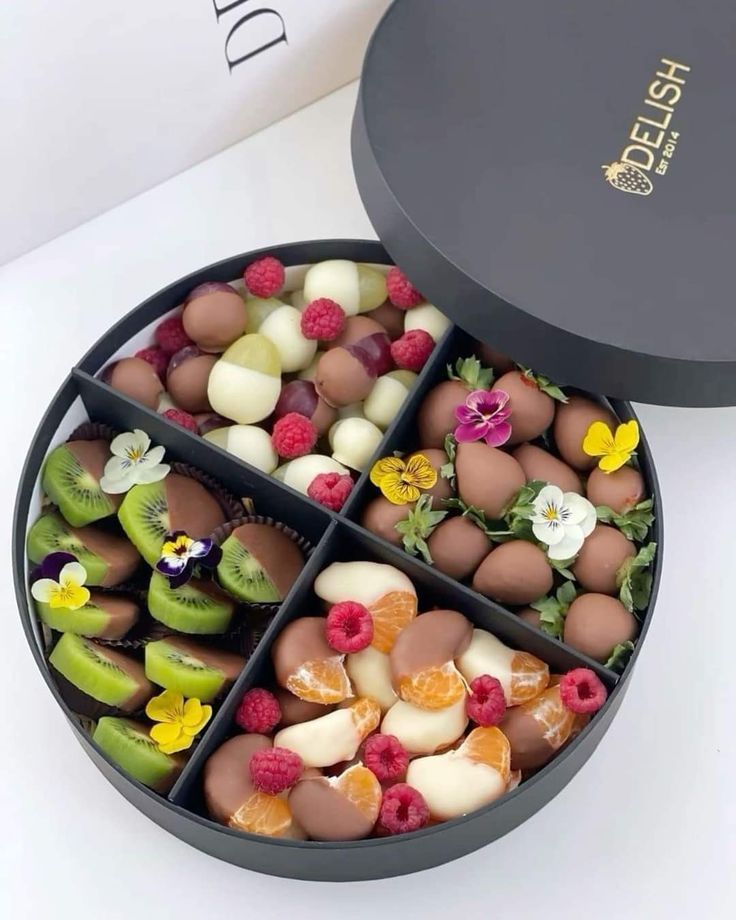 four compartments filled with assorted candies in a black box on a white table