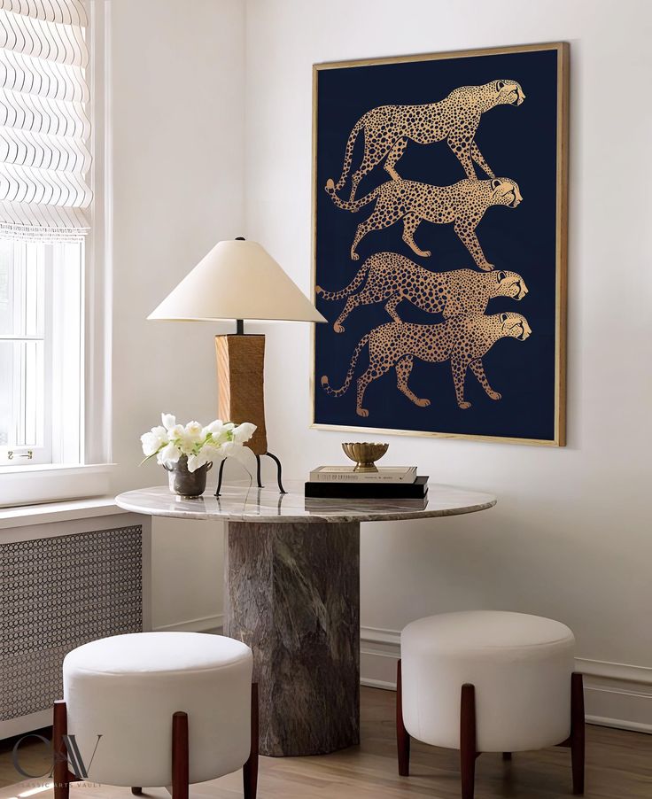 a table with two stools and a painting on the wall in a living room