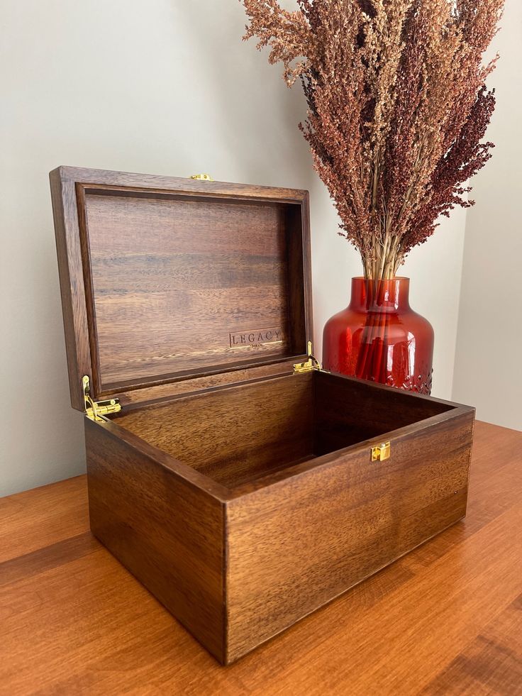 a wooden box sitting on top of a table next to a vase