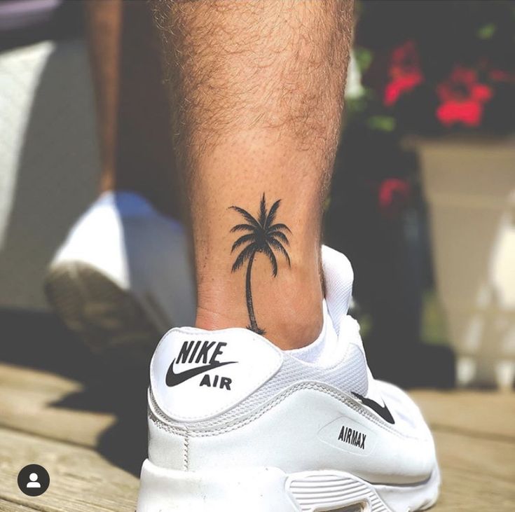 a man with a palm tree tattoo on his foot is standing on a wooden bench