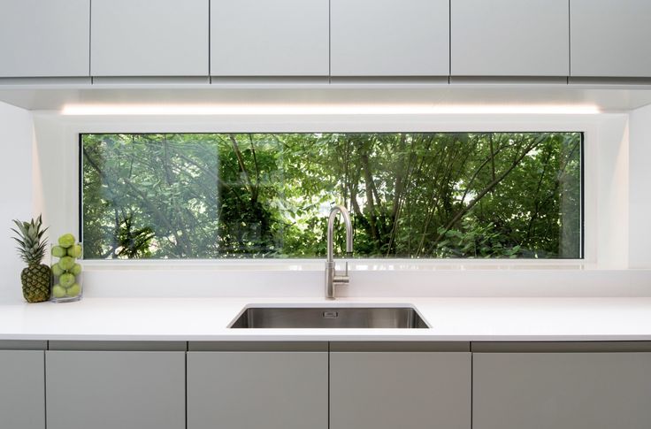 a kitchen with a sink, window and counter top in front of trees outside the window