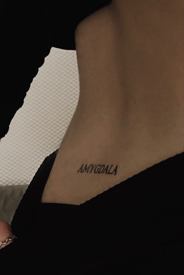 a woman with a small tattoo on her lower back neck and the word amonla written in cursive font