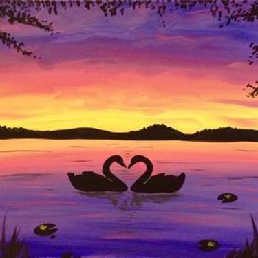 two swans in the water making a heart shape with their necks as the sun sets