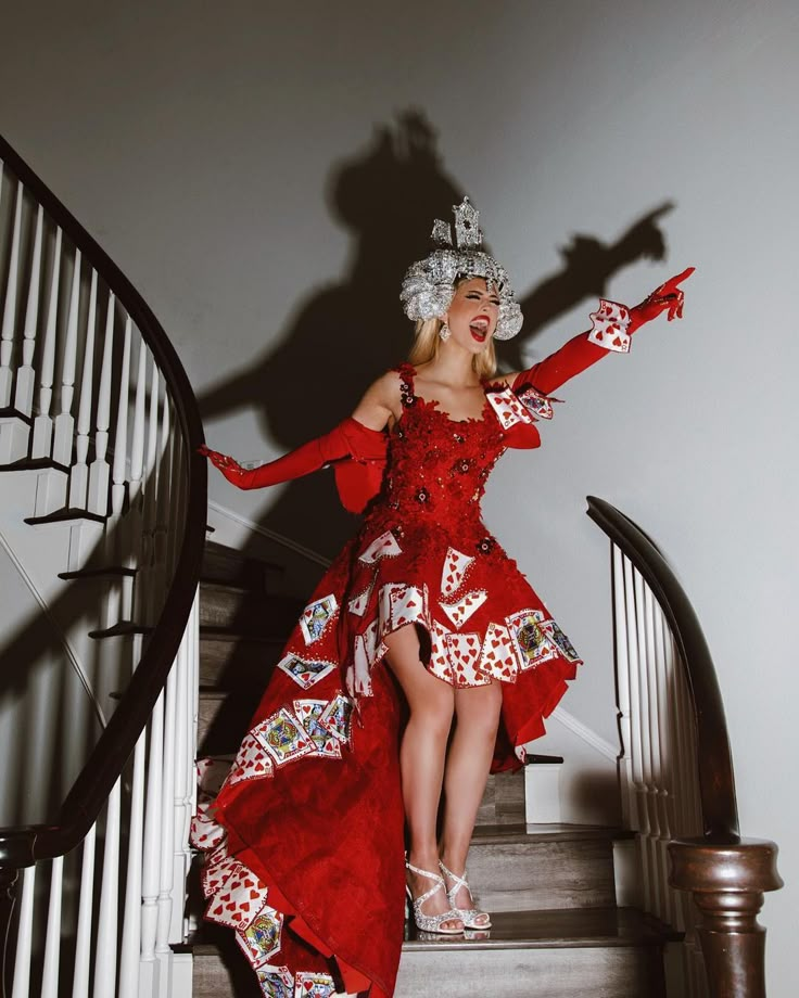 a woman in a red dress is standing on the stairs with her arms outstretched and hands out