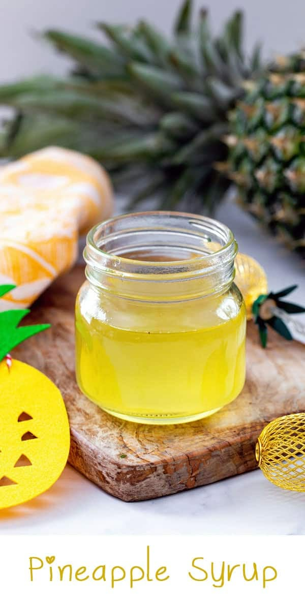 pineapple syrup in a glass jar next to sliced pineapples