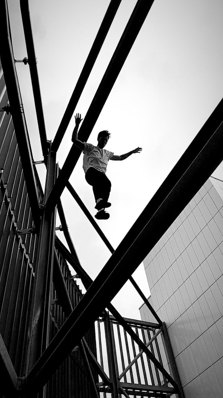 a man riding a skateboard down the side of a metal hand rail next to a tall building