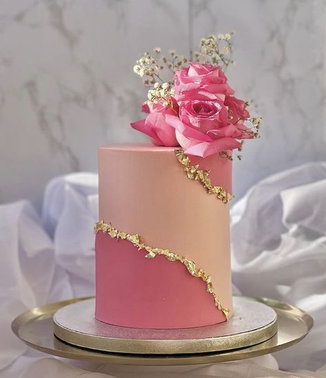 a pink and gold cake with flowers on top