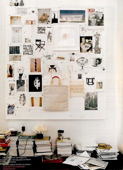 a white wall covered in pictures and books next to a table with a bag on it