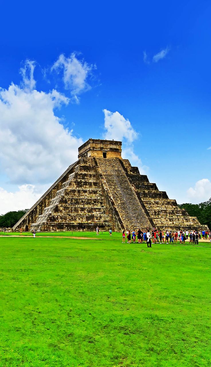 an ancient pyramid in the middle of a green field with people standing around it and looking up