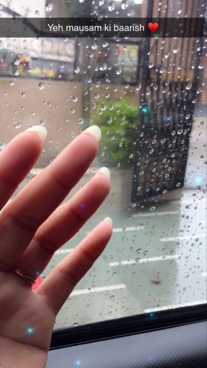 someone holding their hand out the window in front of raindrops on a rainy day