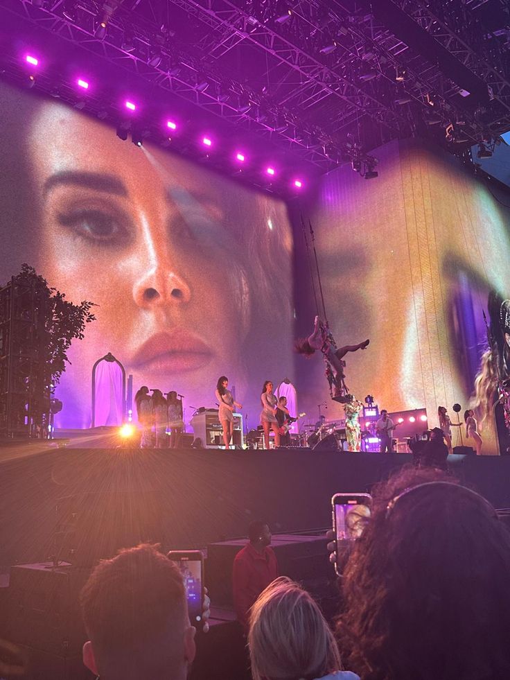 a group of people standing on top of a stage next to a giant projection screen