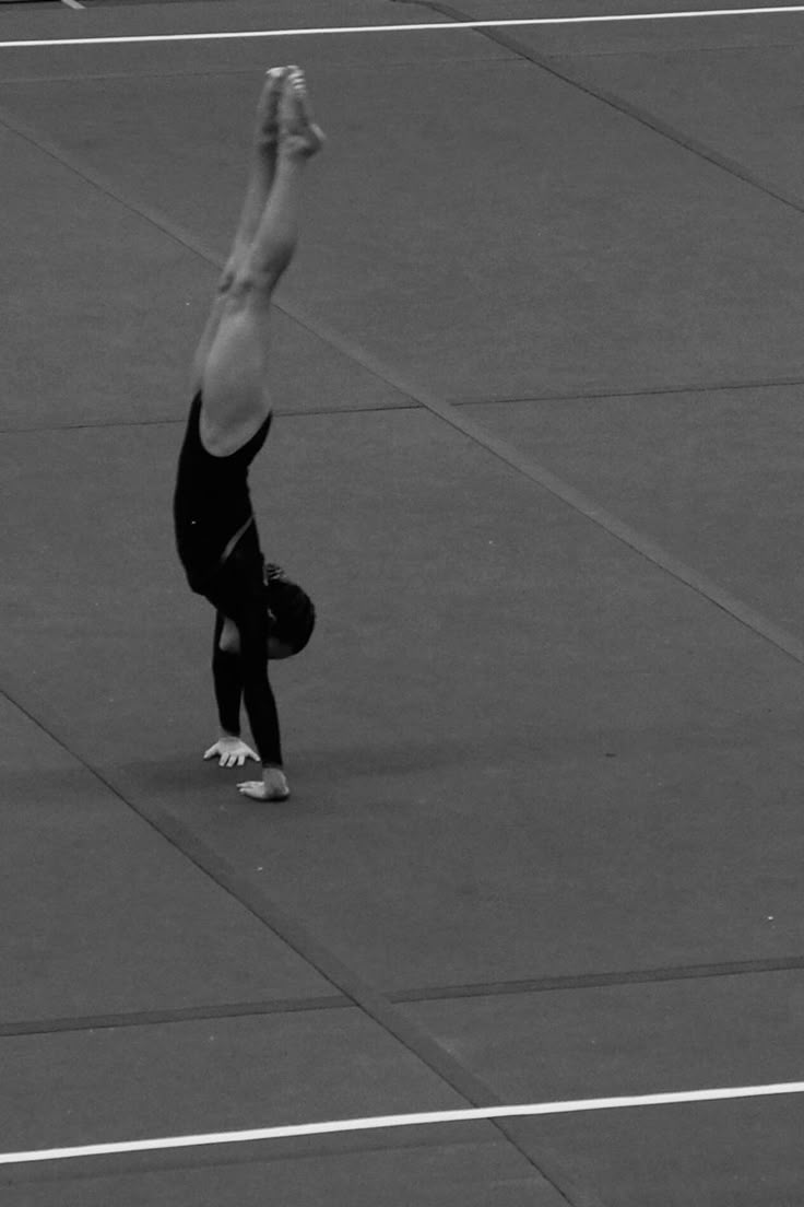 a man doing a handstand on top of a tennis court in black and white