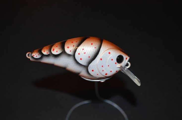 a small plastic toy fish on a black surface with red dots in it's eyes