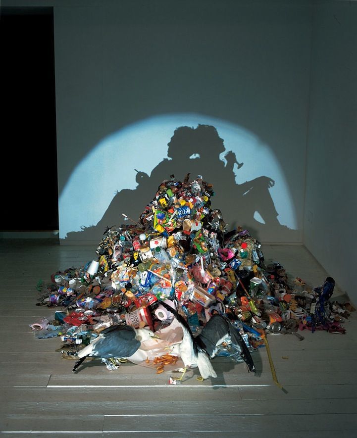 the shadow of a man is cast over a pile of garbage