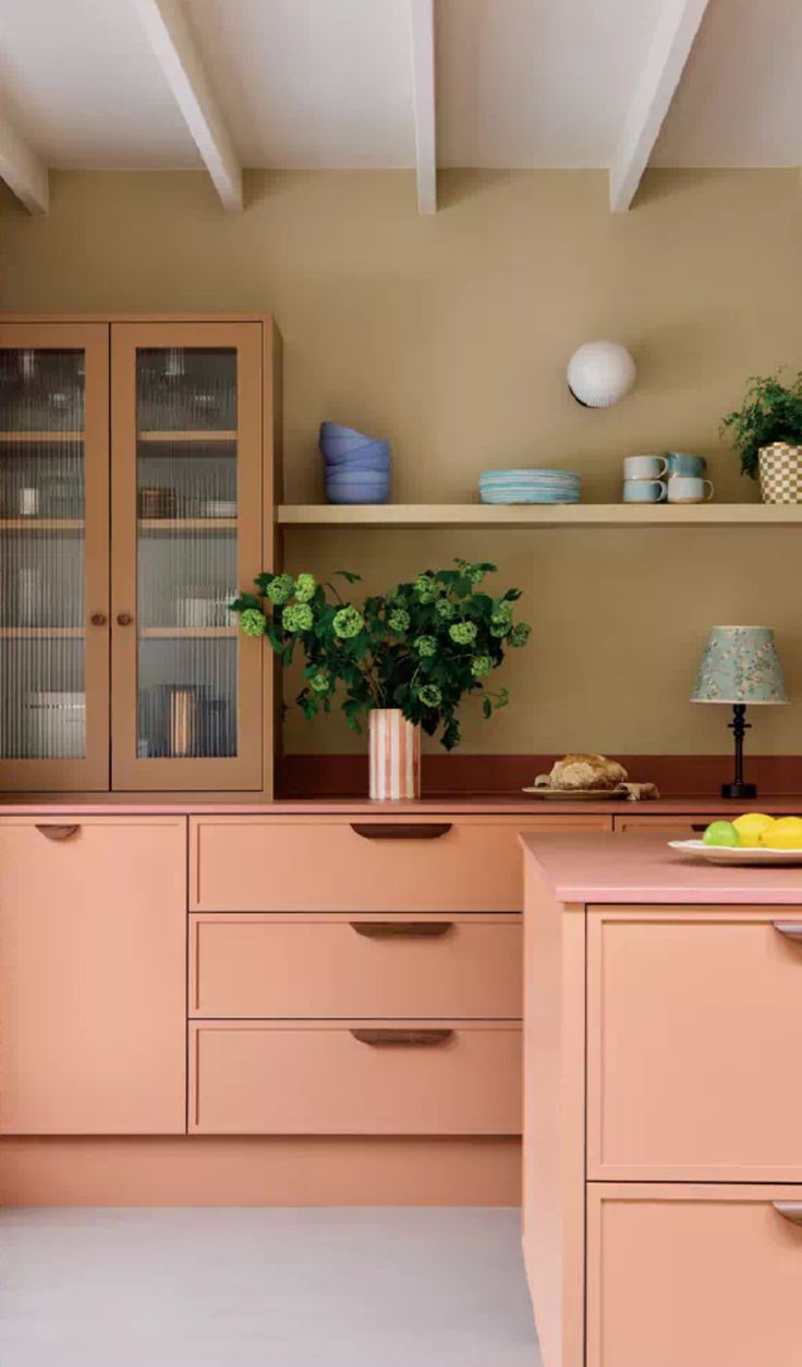 a kitchen with pink cabinets and white flooring is pictured in this image, there are two vases on the counter