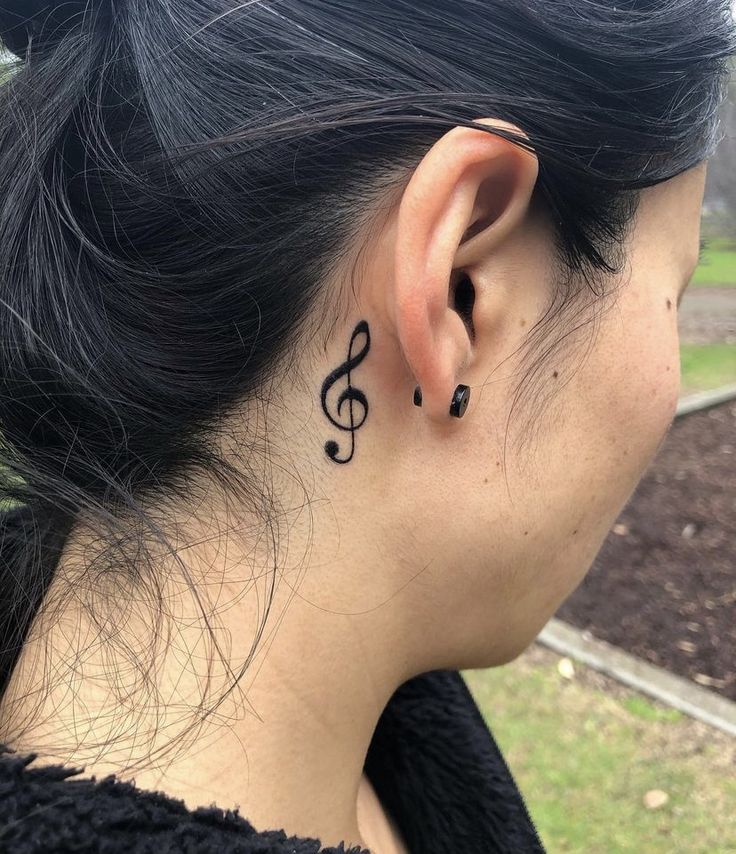 a woman's ear has a musical note tattoo on it