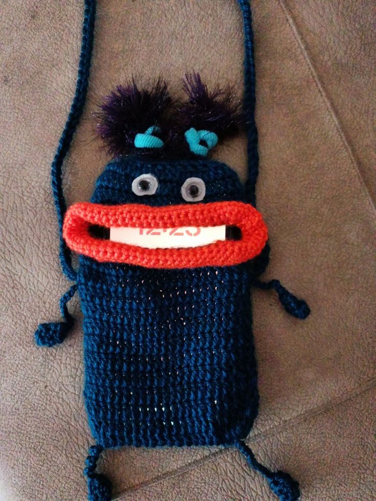 a crocheted cell phone case with an ugly looking creature on it's side