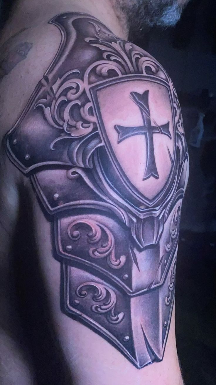 a man with a cross and shield tattoo on his arm