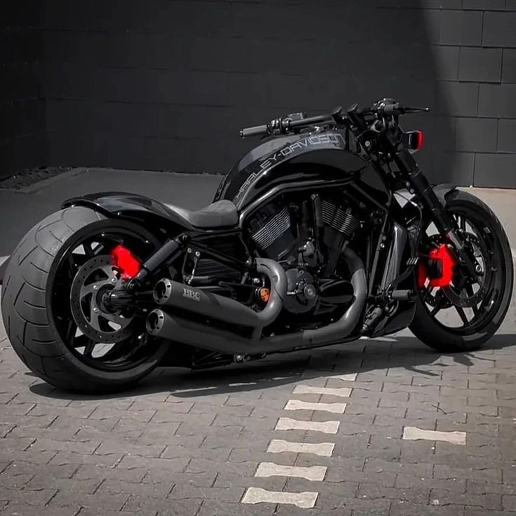 a black motorcycle parked in front of a building on a brick road with red lights