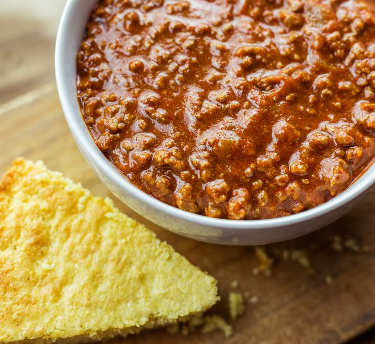 a bowl of chili next to a piece of bread