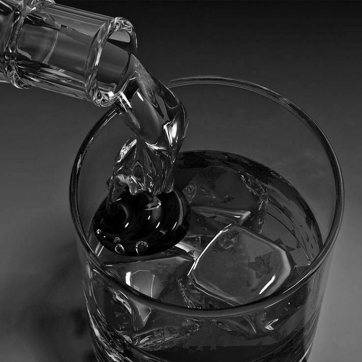 a glass filled with ice cubes and water being poured into the glass to drink