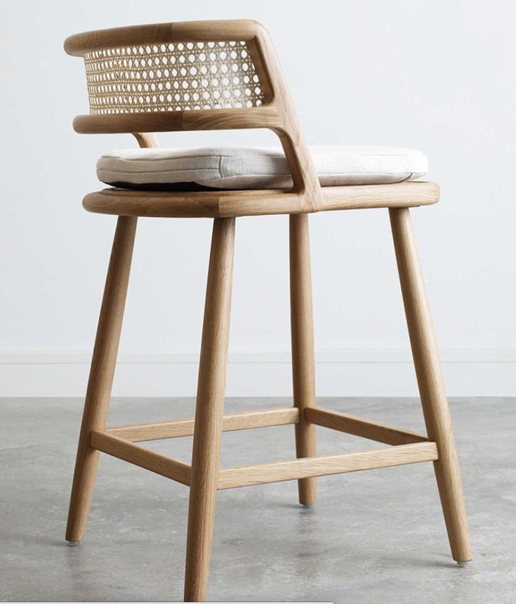 a wooden stool with a white cushion on the seat and back rests against a wall