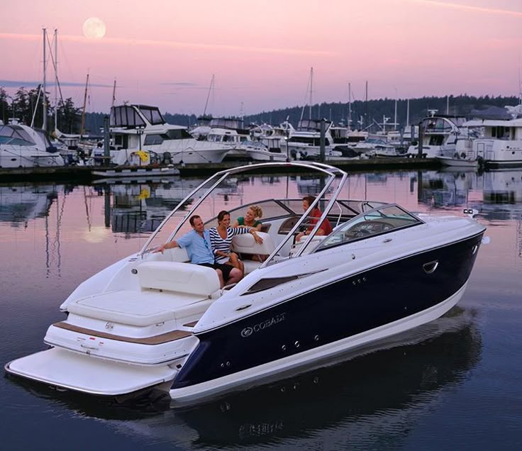 two people are sitting on the back of a boat in the water at sunset with other boats