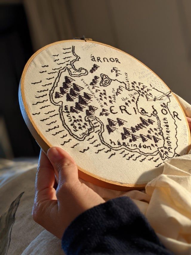 a person holding a cross stitch map in their hand