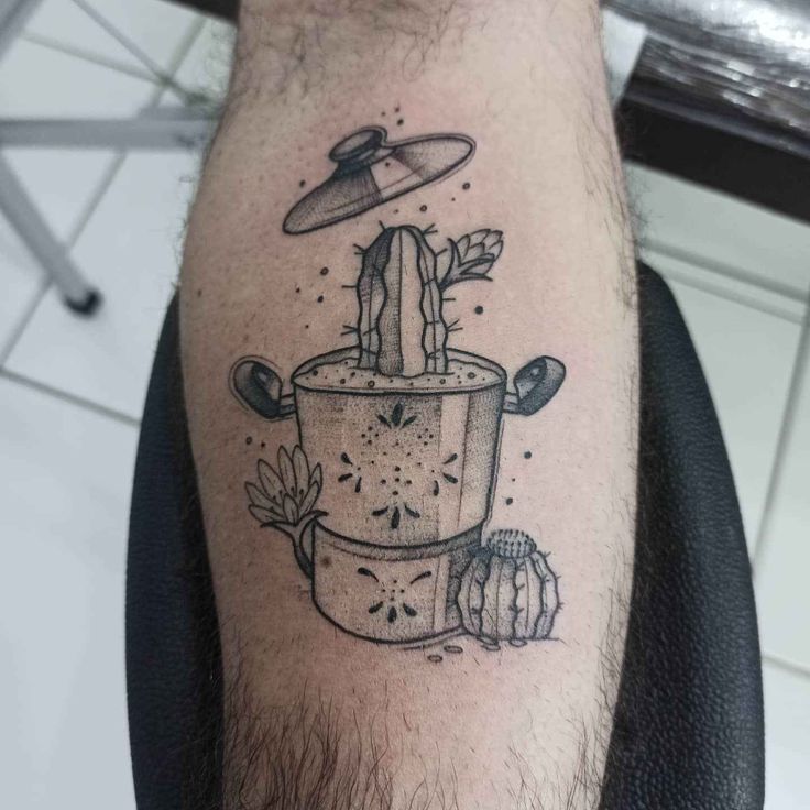 a man's leg with a tattoo on it that has an alien spaceship above the pot